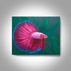 Puede incluir: Una pintura de un pez betta rosa con una aleta caudal azul y roja, nadando en un fondo verde frondoso.