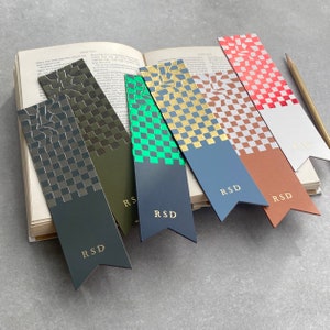 May include: Five different coloured bookmarks with a checkered pattern and gold accents. Each bookmark has a gold "RSD" logo at the bottom.