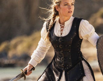 May include: A woman in a medieval-style outfit, holding a sword and shield. She wears a white blouse with a laced neckline, a black leather vest with buckles, and a long braid. The background is a blurred outdoor scene.