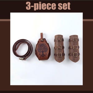 May include: A brown leather 3-piece set. The set includes a rolled belt with a gold buckle, a pouch with a tree design, and two arm cuffs with buckles. The text "3-piece set" is at the top.