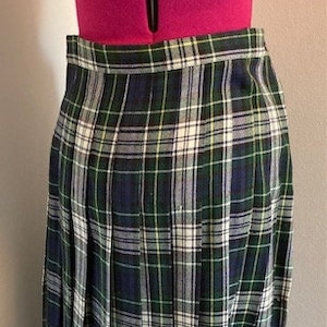 May include: A pleated skirt with a green, white, and blue plaid pattern. The skirt is knee-length and has a fitted waistband.