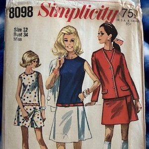 May include: A vintage sewing pattern for a mini-length dress and a jacket. The pattern is Simplicity 8098, size 12, bust 34, for misses. The dress is white with a blue top and the jacket is red with gold buttons.