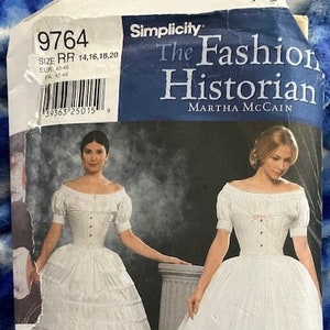 May include: A Simplicity pattern for a white, full-skirted dress with a fitted bodice. The pattern number is 9764 and the size range is 14-20. The pattern is titled "The Fashion Historian" by Martha McCain.