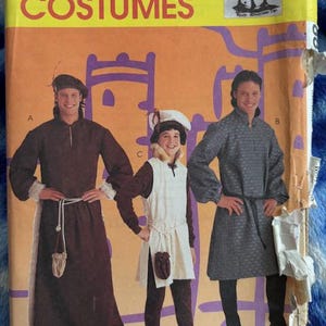 May include: A vintage McCall's Costumes pattern envelope featuring illustrations of medieval costumes. The cover displays three figures in different outfits, including a long brown robe, a white tunic, and a patterned gray tunic. The text "McCall's Costumes" is prominently displayed.