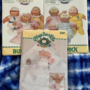 May include: Three vintage Cabbage Patch Kids sewing pattern envelopes. The envelopes feature illustrations of Cabbage Patch Kids dolls in various outfits. The patterns are for preemie-sized dolls and include the Butterick brand.