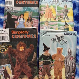 May include: Four Simplicity sewing pattern envelopes for The Wizard of Oz costumes. The envelopes feature illustrations of children wearing outfits representing characters like Dorothy, the Tin Man, the Scarecrow, and the Cowardly Lion, with pattern numbers 390, 4024, 325, and 4133.