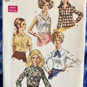 May include: A vintage Simplicity sewing pattern for a women's blouse. The pattern includes four different styles of blouses, including a sleeveless blouse, a short-sleeved blouse, a long-sleeved blouse with a tie, and a long-sleeved blouse with a paisley print. The pattern is for size 12, bust 34, and is labeled "New Sizing".