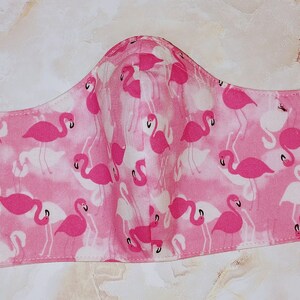 May include: Pink face mask with a flamingo print. The mask has elastic ear loops.