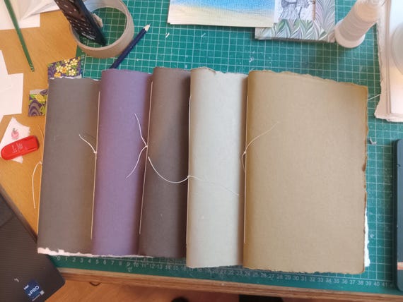 Pamphlet stitched cotton rag sketchbooks with coloured paper cover. A5 or A6 portrait. 20 leaves / 40 sides mid rough texture