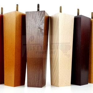 May include: Six wooden furniture legs in various colors, including red, orange, brown, natural, dark brown, and light brown. Each leg has a square top and a tapered bottom.