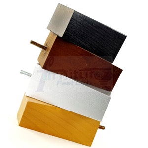 May include: Four wooden furniture legs in different colors: black, brown, silver, and natural wood. Each leg has a metal screw for attaching to furniture.