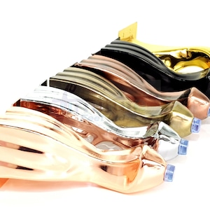 Puede incluir: Un conjunto de siete patas de muebles decorativas en varios acabados metálicos, incluyendo oro, plata, cobre y negro. Las patas tienen todas el mismo diseño, con una forma curva y un detalle decorativo en la parte superior.