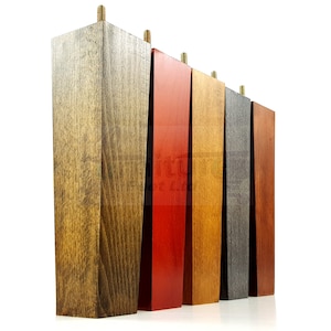 May include: Five wooden furniture legs in different stained colors: dark brown, red, orange, gray, and brown. The legs are all the same size and shape, with a square top and a tapered bottom.