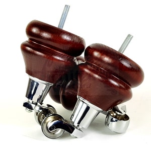 May include: Two dark brown wooden furniture legs with a decorative, curved design. Each leg has a chrome-colored metal base with a caster wheel for easy movement. The legs have a threaded bolt for attachment.