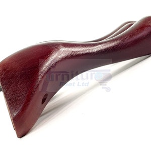 Może przedstawiać: Drewniana noga meblowa w kolorze ciemnoczerwonym o zakrzywionym kształcie, z gwintowanym śrubą metalową do mocowania do mebli.