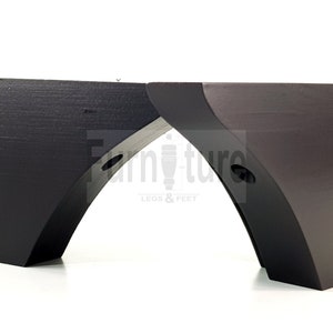 Könnte beinhalten: Zwei schwarze Möbelbeine aus Holz mit einem geschwungenen Design. Die Beine haben eine glatte Oberfläche und sind für die Befestigung an Möbeln konzipiert.