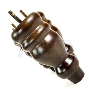 May include: A dark brown wooden furniture leg with a decorative, fluted design. The leg has three threaded metal screws for attaching to furniture.