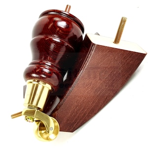 Könnte beinhalten: Ein Satz aus zwei Möbelbeinen aus Holz mit einem Messingrollenrad. Ein Bein ist gedreht und abgerundet, während das andere flach und abgewinkelt ist. Beide Beine sind in einem dunklen Rotbraun gebeizt.