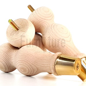 Könnte beinhalten: Drei Holzbeine für Möbel mit Messingspitze. Die Beine sind unbehandelt und haben eine abgerundete Form.