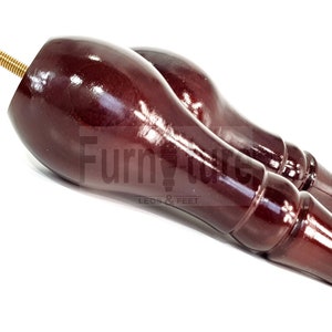 Może przedstawiać: Dwa ciemnobrązowe drewniane nóżki do mebli z gwintowanym śrubą metalową. Nóżki mają błyszczące, polerowane wykończenie.