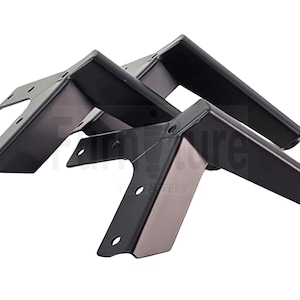 May include: Three angled, black metal furniture legs. Each leg has a flat top with pre-drilled holes for mounting and a tapered, rectangular base. The legs are designed for furniture support and have a modern aesthetic.