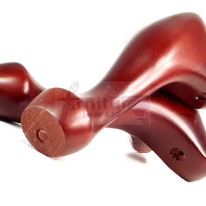 Puede incluir: Dos patas de muebles de madera de color marrón rojizo. Las patas son curvadas y tienen un acabado liso.