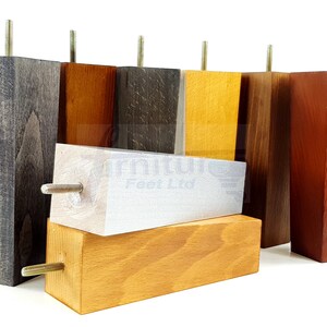 May include: Assortment of wooden furniture legs in various wood stains, including gray, brown, white, yellow, and red. Each leg has a metal screw for attaching to furniture.
