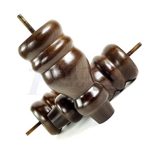 May include: Two dark brown wooden furniture legs with a threaded metal screw for attaching to furniture. The legs have a rounded, bulbous shape.