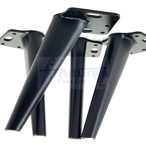 Puede incluir: Cuatro patas de muebles de metal negro con una placa de montaje cuadrada. Cada pata mide aproximadamente 25 cm de alto.