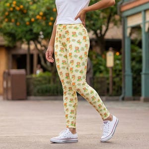 A woman wearing a white shirt and leggings with a pattern of yellow and orange flowers is standing in front of a building with a sign that says "Citrus Swirl".