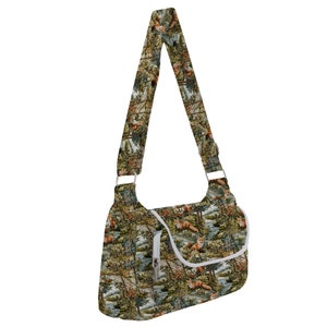 May include: A green, brown, and white shoulder bag with a fox print. The bag has a zipper closure and a long adjustable strap.