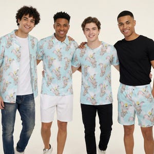 Peut inclure: Une collection de vêtements avec un motif bleu clair représentant l'éléphant Dumbo. Les articles comprennent une chemise à manches courtes, un polo, un t-shirt et un short à cordon, tous arborant le même imprimé répétitif du personnage.