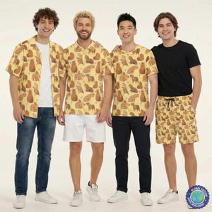 May include: Four people wearing matching capybara-patterned shirts and shorts. The shirts are yellow with brown capybara illustrations. One person wears a black t-shirt and shorts with the same pattern. The group is standing in front of a white background.
