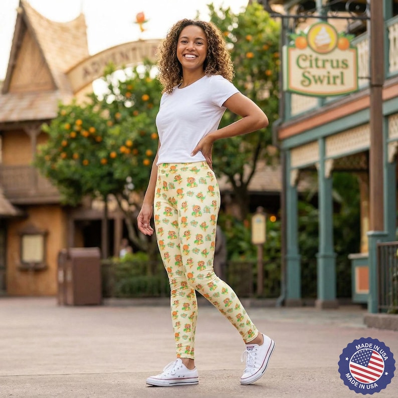 A woman wearing a white shirt and leggings with a pattern of yellow and orange flowers is standing in front of a building with a sign that says "Citrus Swirl".