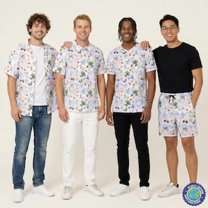 May include: A collection of apparel featuring a light-coloured fabric with a repeating pattern of colourful cartoon-style icons including trees, castles, and bows. The set includes a short-sleeved button-down shirt, a t-shirt, and drawstring shorts.