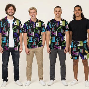 May include: A collection of apparel featuring a black fabric base with a repeating colourful graphic pattern of abstract shapes, including purple, blue, and green elements. The set includes a short-sleeve button-down shirt, a polo shirt, a t-shirt, and shorts.