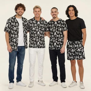 Puede incluir: Cuatro personas visten ropa con un estampado pirata en blanco y negro que incluye calaveras, timones de barco y pistolas. Los conjuntos incluyen una camisa de manga corta, un polo, una camiseta y pantalones cortos, combinados con jeans o pantalones.