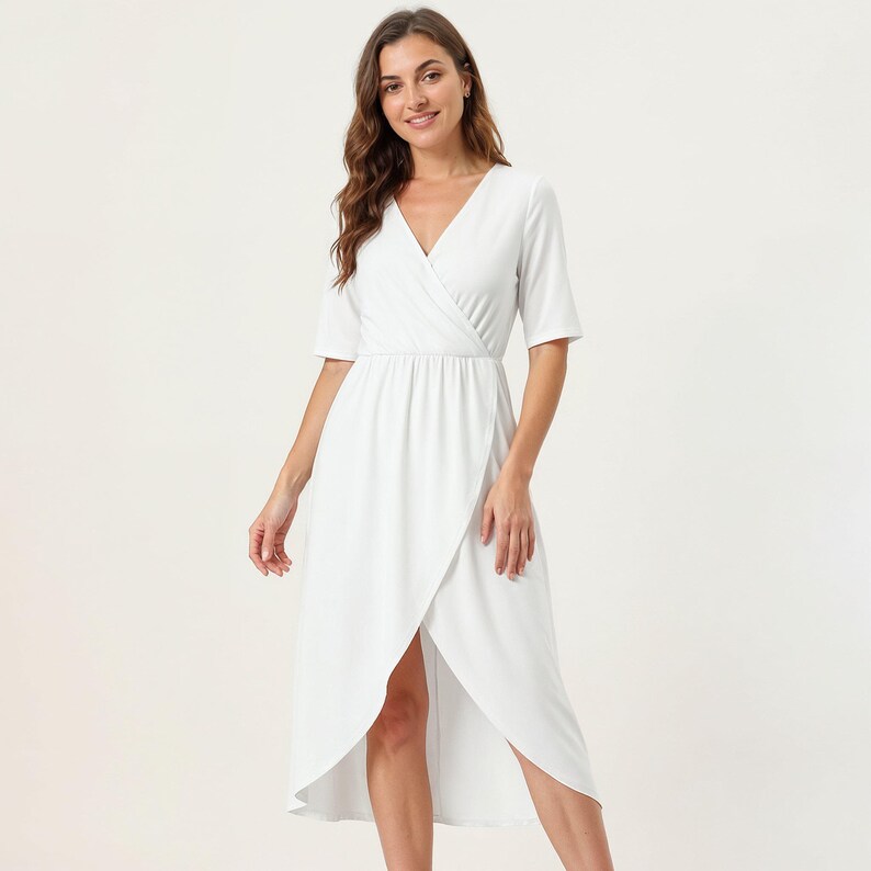 A woman wearing a white wrap dress with a high slit and a wrap neckline, smiling at the camera.