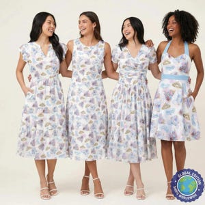 May include: Four women wearing white dresses with a repeating pattern of castles, clouds, and crowns in blue, purple, and gold. The dresses have different styles, including flutter sleeves, sleeveless, and halter neck. The dresses are knee-length and paired with white heels.