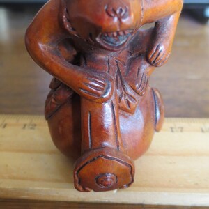 May include: A wooden monkey figurine with brown fur, holding a wooden stick. The monkey has a round, brown body and a detailed face with black eyes.