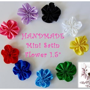 May include: Assortment of 10 handmade satin mini flowers in various colors, each measuring 1.5 inches in diameter. The flowers are arranged in a circle on a white background. The text "HANDMADE Mini Satin Flower 1.5" is written in pink letters in the center of the circle. The image also includes a logo for "Just Dog Gone Cute".
