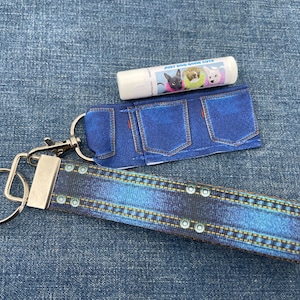 May include: A blue denim keychain with a silver key ring and a matching lip balm holder with the text "Just Dog Gone Cute".