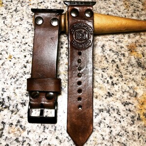 May include: Two brown leather watch straps with metal clasps and rivets. The strap on the right has the text "Genuine Leather" and "N&L" embossed on it.