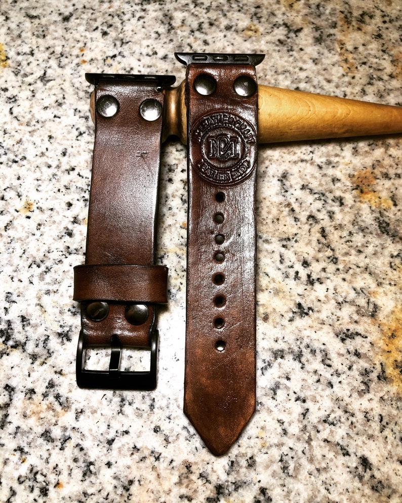May include: Two brown leather watch straps with metal clasps and rivets. The strap on the right has the text "Genuine Leather" and "N&L" embossed on it.