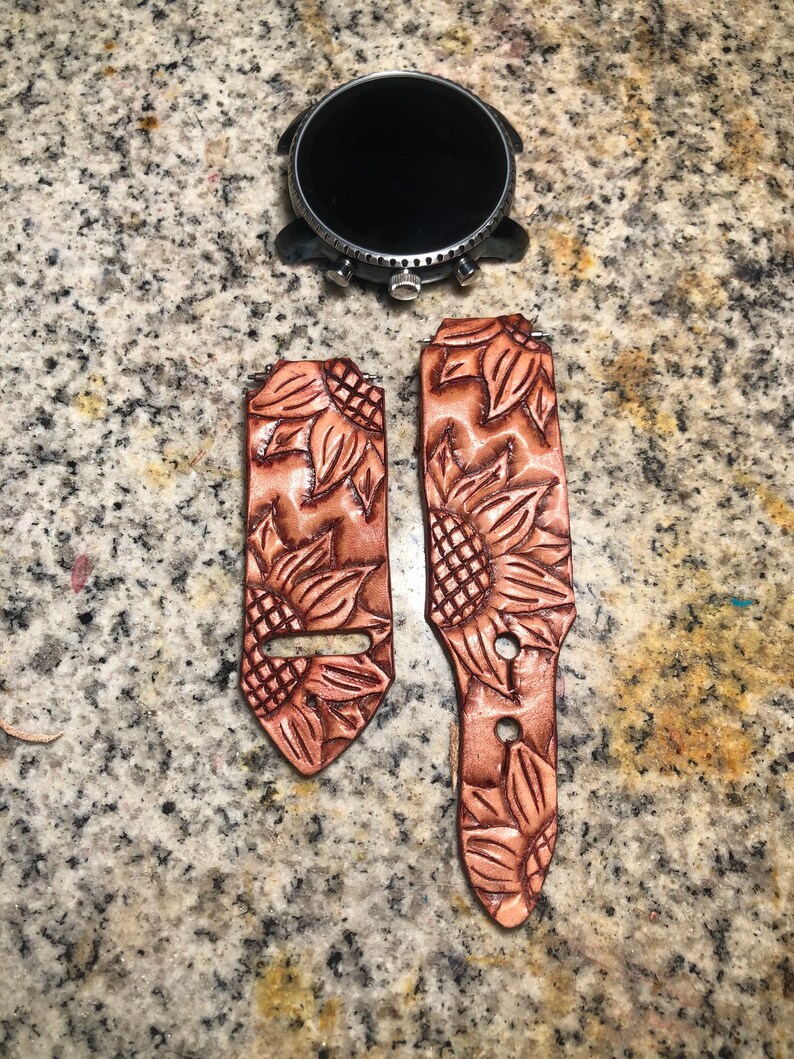 May include: Two brown leather watch straps with a sunflower design. The straps are for a smartwatch.