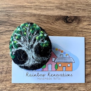 Puede incluir: Un broche de árbol de fieltro con hojas verdes y un tronco blanco. El broche está en una tarjeta blanca con el texto "Rainbow Renovations Handmade Gifts".