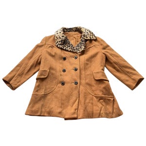 May include: A tan double-breasted coat with a leopard print collar. The coat has two front pockets and black buttons. The sleeves are long and the coat is made of a soft material.