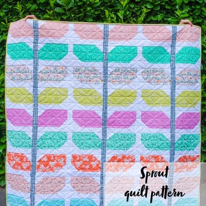 May include: A colorful quilt with a pattern of green, pink, and orange leaves. The quilt is made with a variety of fabrics and has a white background. The quilt is titled "Sprout quilt pattern" and "Lou Orth Designs".