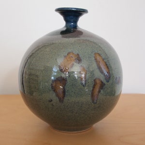 May include: A round ceramic vase with a blue neck and a green glaze with brown accents.