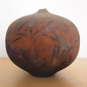 May include: A large, round, brown ceramic vase with a textured surface and black markings.